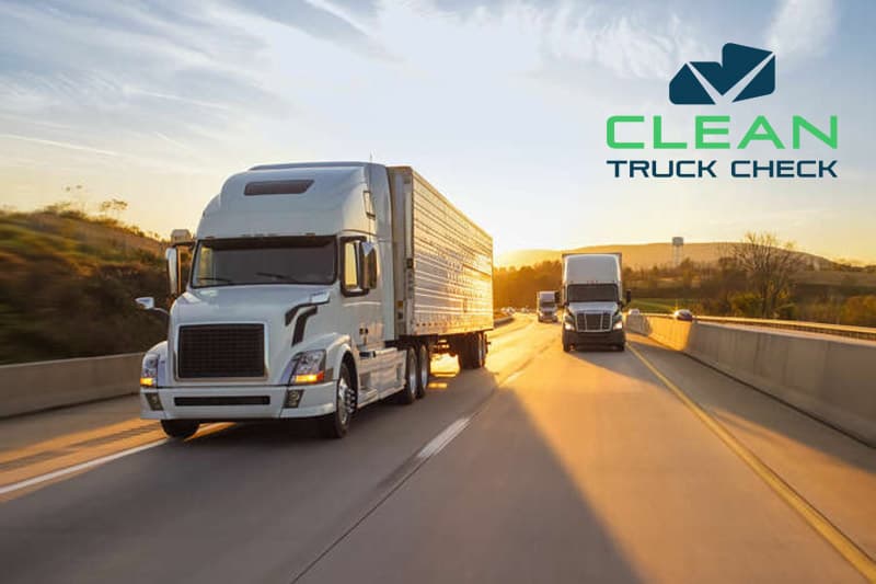 Semi trucks driving on a highway at sunset
